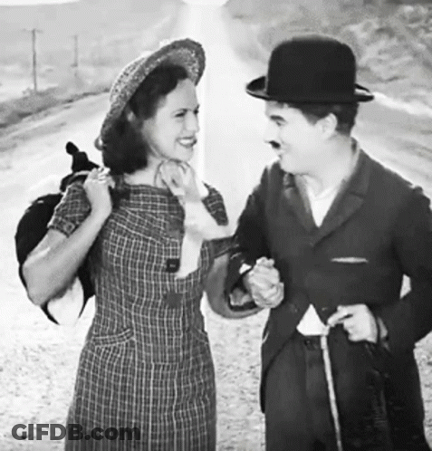 A Black And White Photo Of A Man And Woman Standing Next To Each Other GIF