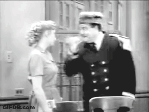 A Black And White Photo Of A Man And Woman Talking To Each Other GIF