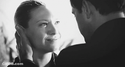 A Black And White Photo Of A Man And Woman Touching Each Other 'S Faces . GIF
