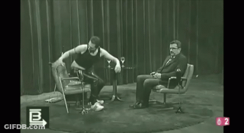 A Black And White Photo Of A Man Dancing In Front Of A Man Sitting In A Chair With The Number 2 On The Bottom GIF