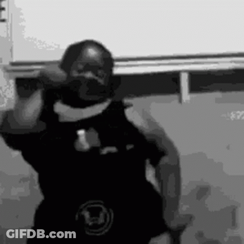A Black And White Photo Of A Man Dancing In Front Of A White Wall . GIF