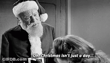 A Black And White Photo Of A Man Dressed As Santa Claus Talking To A Woman . GIF