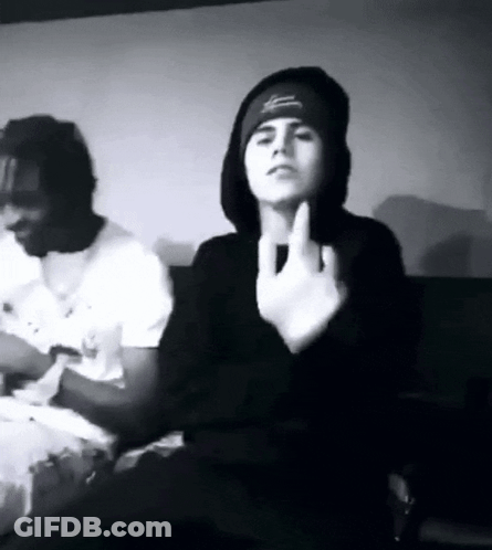 A Black And White Photo Of A Man Giving The Middle Finger While Sitting Next To Another Man . GIF
