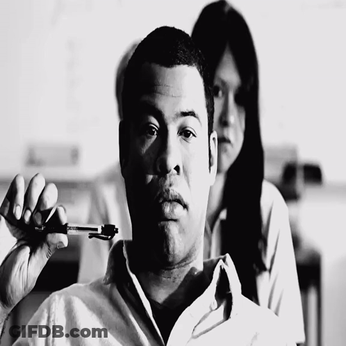 A Black And White Photo Of A Man Holding A Pen In His Hand GIF
