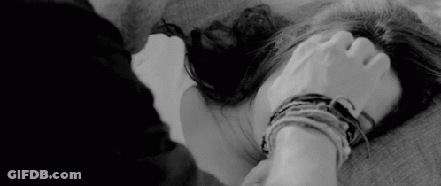 A Black And White Photo Of A Man Holding A Woman 'S Hand While Laying On A Bed . GIF