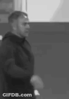A Black And White Photo Of A Man In A Black Jacket Standing In A Room . GIF