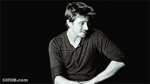 A Black And White Photo Of A Man In A Black Shirt Making A Funny Face . GIF