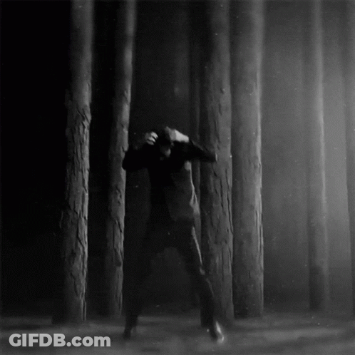 A Black And White Photo Of A Man In A Forest GIF