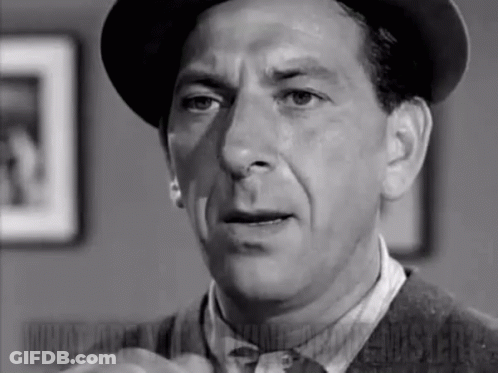 A Black And White Photo Of A Man In A Hat And Tie . GIF
