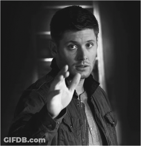 A Black And White Photo Of A Man In A Jacket Making A Gesture With His Hand GIF
