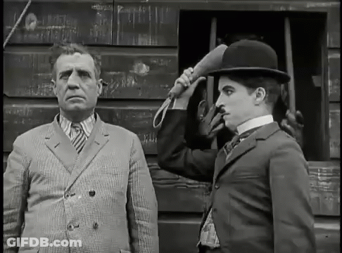 A Black And White Photo Of A Man In A Suit And A Man In A Bowler Hat GIF