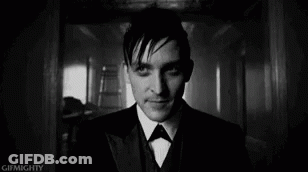A Black And White Photo Of A Man In A Suit And Bow Tie Looking At The Camera . GIF