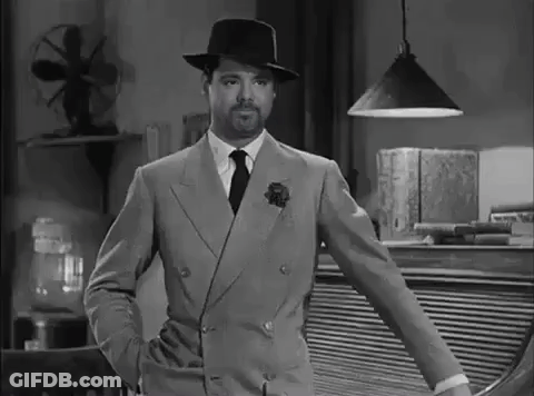 A Black And White Photo Of A Man In A Suit And Hat GIF