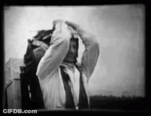 A Black And White Photo Of A Man In A Suit And Tie Adjusting His Tie . GIF
