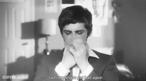 A Black And White Photo Of A Man In A Suit And Tie Covering His Mouth . GIF