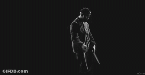 A Black And White Photo Of A Man In A Suit And Tie Dancing In The Dark . GIF