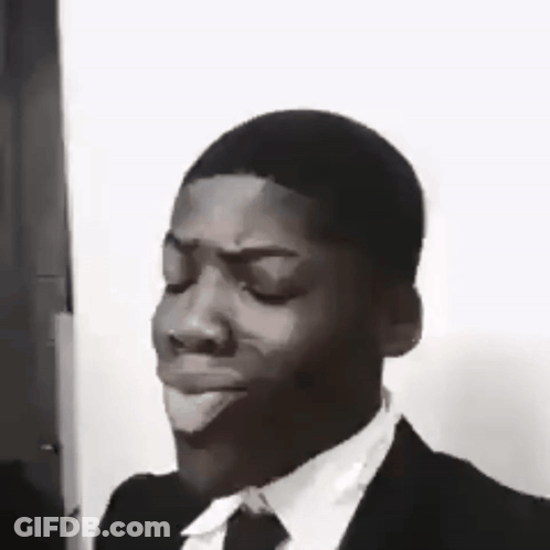 A Black And White Photo Of A Man In A Suit And Tie Making A Face . GIF