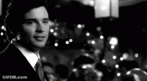 A Black And White Photo Of A Man In A Suit And Tie Standing In Front Of A Crowd . GIF