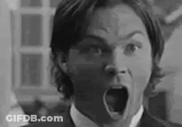 A Black And White Photo Of A Man In A Suit And Tie With His Mouth Open . GIF