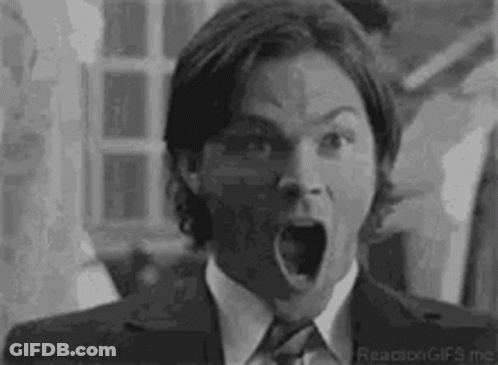 A Black And White Photo Of A Man In A Suit And Tie With His Mouth Wide Open . GIF