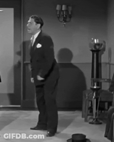 A Black And White Photo Of A Man In A Suit Dancing GIF