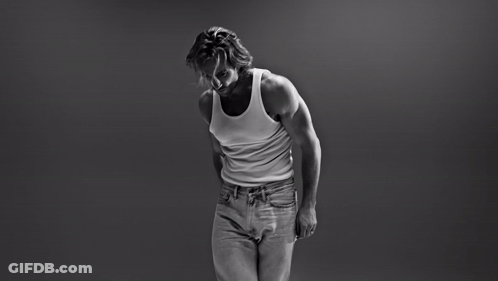 A Black And White Photo Of A Man In A Tank Top And Jeans GIF