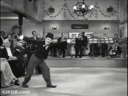 A Black And White Photo Of A Man In A Top Hat Dancing On A Stage . GIF