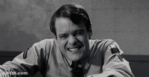 A Black And White Photo Of A Man In A Uniform Laughing GIF