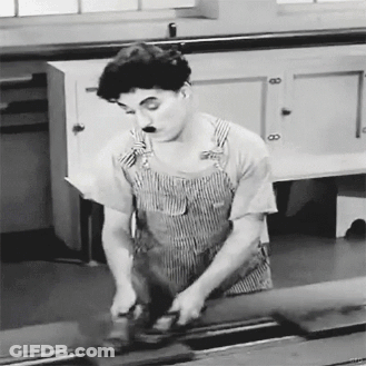 A Black And White Photo Of A Man In Overalls Using A Grinder . GIF