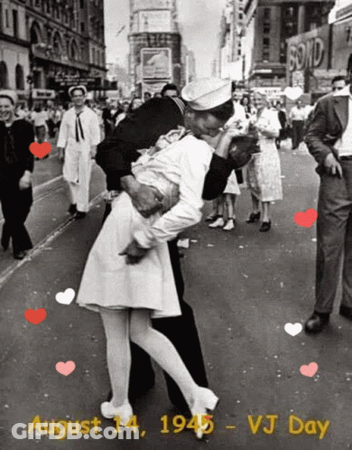 A Black And White Photo Of A Man Kissing A Woman On A City Street GIF