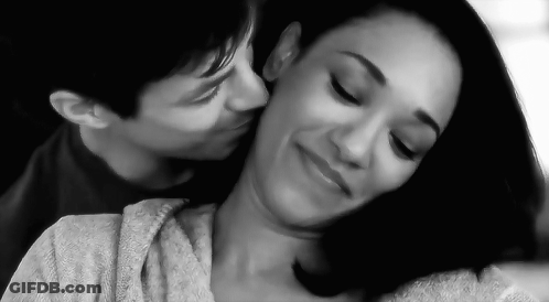 A Black And White Photo Of A Man Kissing A Woman On The Cheek . GIF