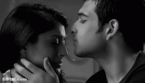 A Black And White Photo Of A Man Kissing A Woman On The Cheek . GIF