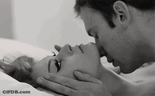 A Black And White Photo Of A Man Kissing A Woman On The Forehead . GIF
