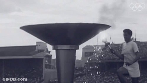 A Black And White Photo Of A Man Lighting A Torch GIF