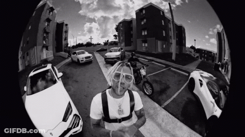 A Black And White Photo Of A Man On A Motorcycle Surrounded By Cars GIF
