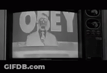 A Black And White Photo Of A Man On A Television Screen With The Word Obey On It . GIF
