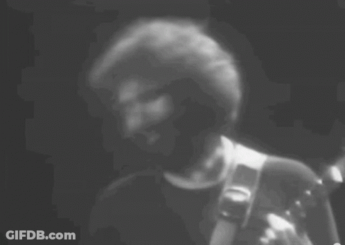 A Black And White Photo Of A Man Playing A Guitar . GIF