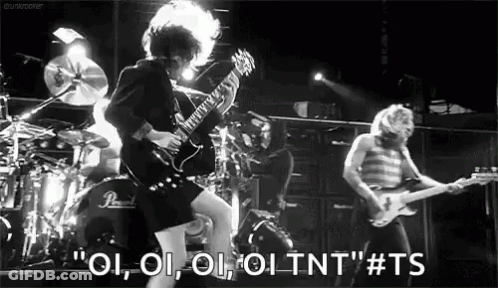 A Black And White Photo Of A Man Playing A Guitar In Front Of A Drum Set . GIF
