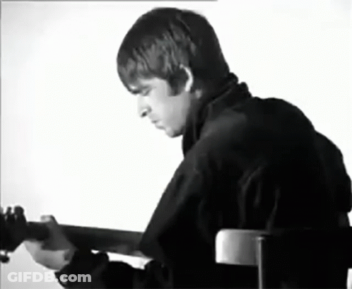 A Black And White Photo Of A Man Playing A Guitar . GIF