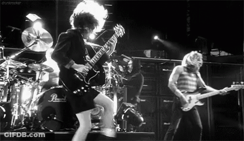 A Black And White Photo Of A Man Playing A Guitar On Stage . GIF