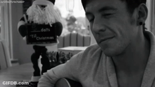 A Black And White Photo Of A Man Playing A Guitar With A Sign That Says Days Till Christmas GIF