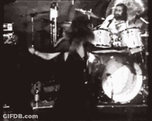 A Black And White Photo Of A Man Playing Drums In A Band GIF
