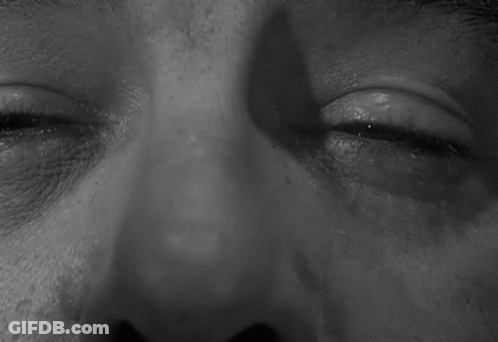 A Black And White Photo Of A Man 'S Eyes With A Shadow On His Face GIF