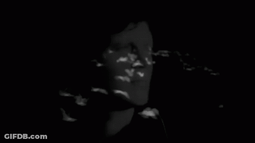 A Black And White Photo Of A Man 'S Face In A Dark Room GIF