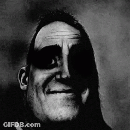 A Black And White Photo Of A Man 'S Face With A Shadow On It . GIF
