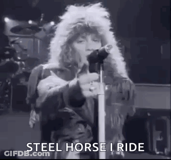 A Black And White Photo Of A Man Singing Into A Microphone On Stage . GIF
