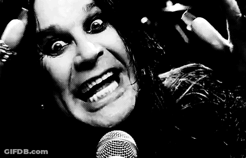 A Black And White Photo Of A Man Singing Into A Microphone With His Mouth Open . GIF