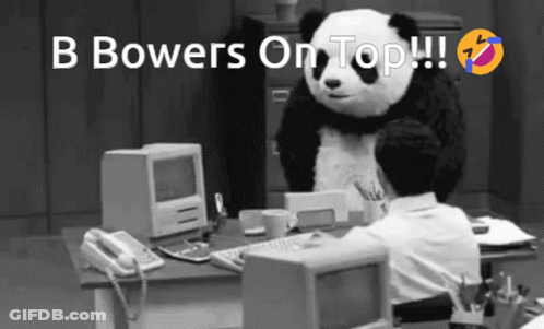 A Black And White Photo Of A Man Sitting At A Desk With A Panda On Top Of Him GIF
