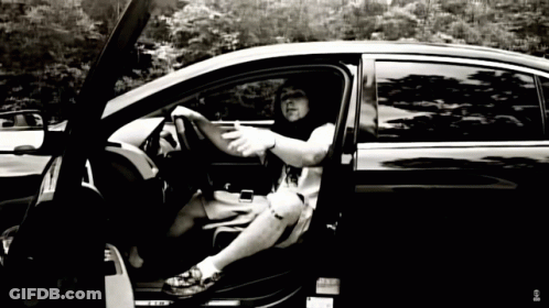 A Black And White Photo Of A Man Sitting In A Car With The Door Open GIF