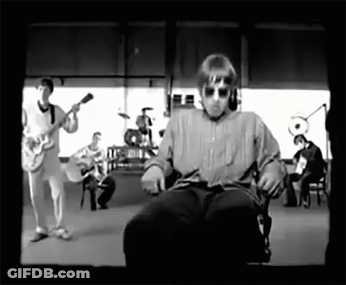 A Black And White Photo Of A Man Sitting In A Chair In Front Of A Band GIF